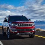 A red 2024 Wagoneer driving on an open road with blue skies.