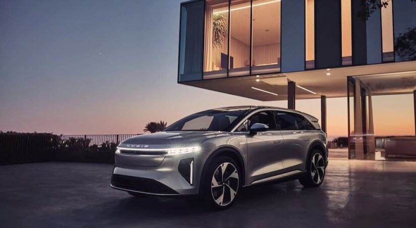 A silver 2025 Lucid Air Gravity is shown parked near a house.