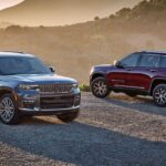 A grey 2024 Jeep Grand Cherokee Summit and a red 2024 Jeep Grand Cherokee Limited parked together in the desert.