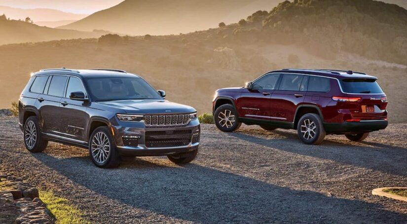 A grey 2024 Jeep Grand Cherokee Summit and a red 2024 Jeep Grand Cherokee Limited parked together in the desert.