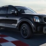 A black 2023 Kia Telluride X-Line driving on a race track.
