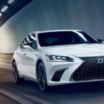 A white 2024 Lexus ES for sale driving through an illuminated tunnel.
