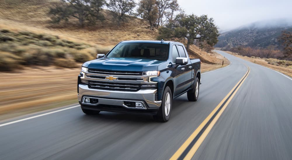 A blue 2020 Chevy Silverado 1500 is shown driving on a highway.
