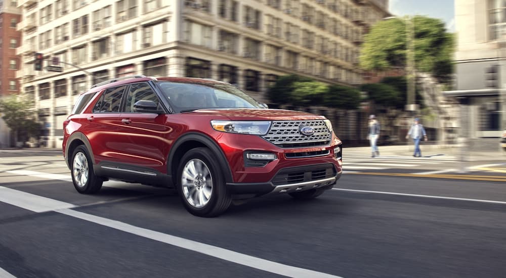 A red 2020 Ford Explorer is shown driving near city buildings.