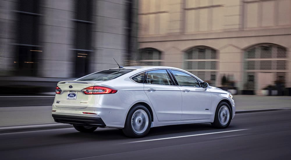 A white 2020 Ford Fusion is shown driving on a city street.