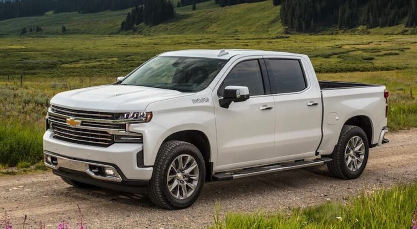 A popular used Chevy Silverado for sale, a white 2021 Chevy Silverado 1500 High Country, is shown parked off-road.