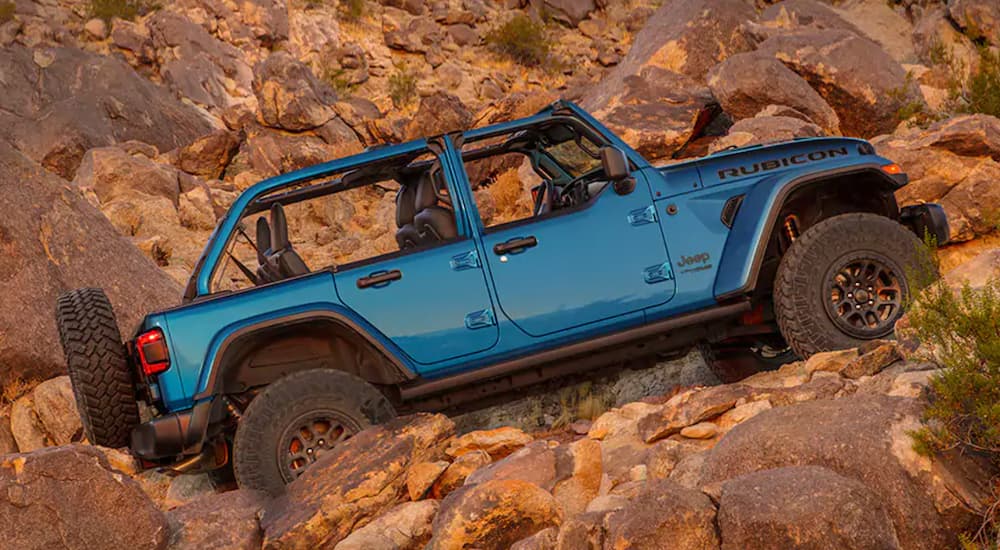 A blue 2021 Jeep Wrangler Rubicon 392 is shown climbing a rocky hill.