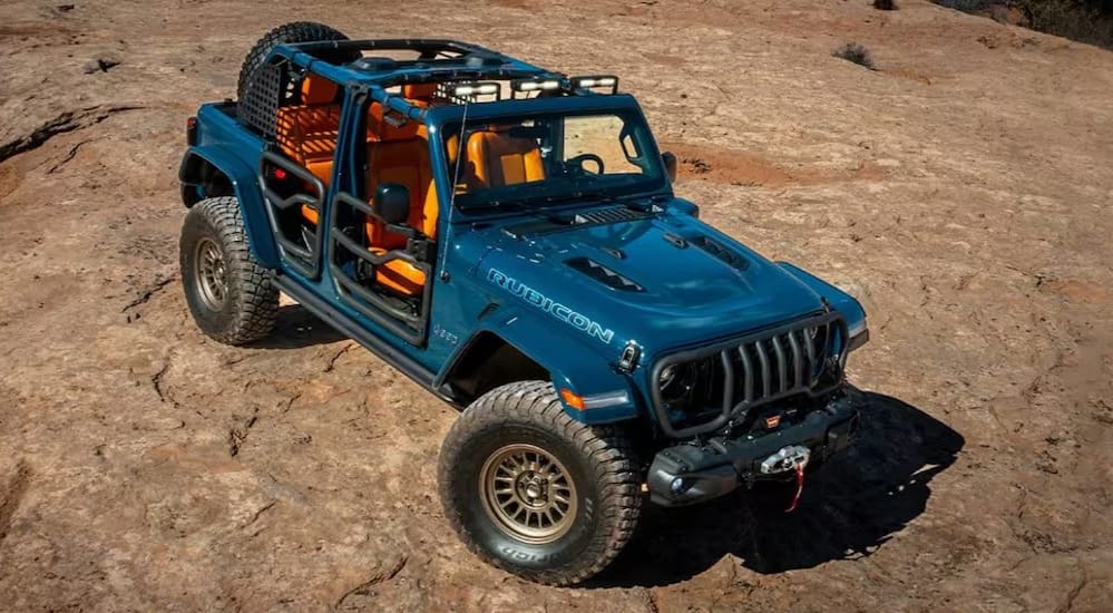 A blue 2023 Jeep Wrangler Rubicon 4xe is shown driving near a cliff.