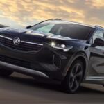 A black 2023 Buick Envision is shown driving on a highway after visiting a Buick dealer.