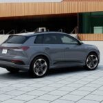 A gray 2024 Audi Q4 e-tron is shown parked near a building.
