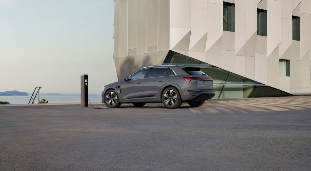 A gray 2024 Audi Q8 e-tron is shown parked and charging.