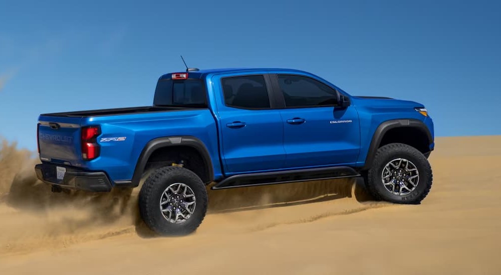 A blue 2024 Chevy Colorado ZR2 is shown driving on sand.