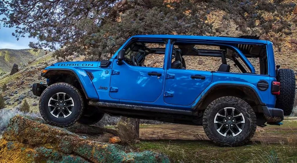 A popular used Jeep Wrangler for sale, a blue 2024 Jeep Wrangler 4xe Rubicon is shown parked off-road.