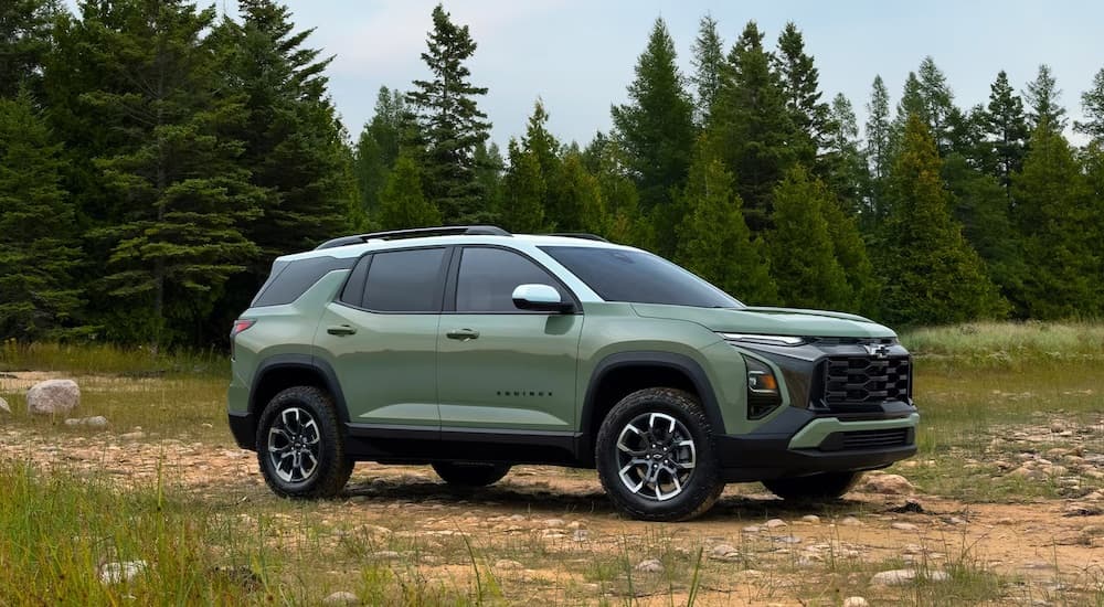 A green 2025 Chevy Equinox is shown driving off-road near a forest.