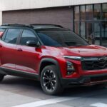 A red 2025 Chevy Equinox is shown driving in a city after visiting a Chevy dealer.