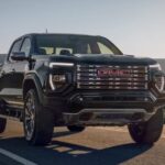 A black 2024 GMC Canyon is shown driving from a dealer with a GMC Canyon for sale.