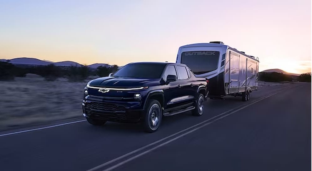 The upcoming black Silverado PHEV RST is shown towing a trailer.