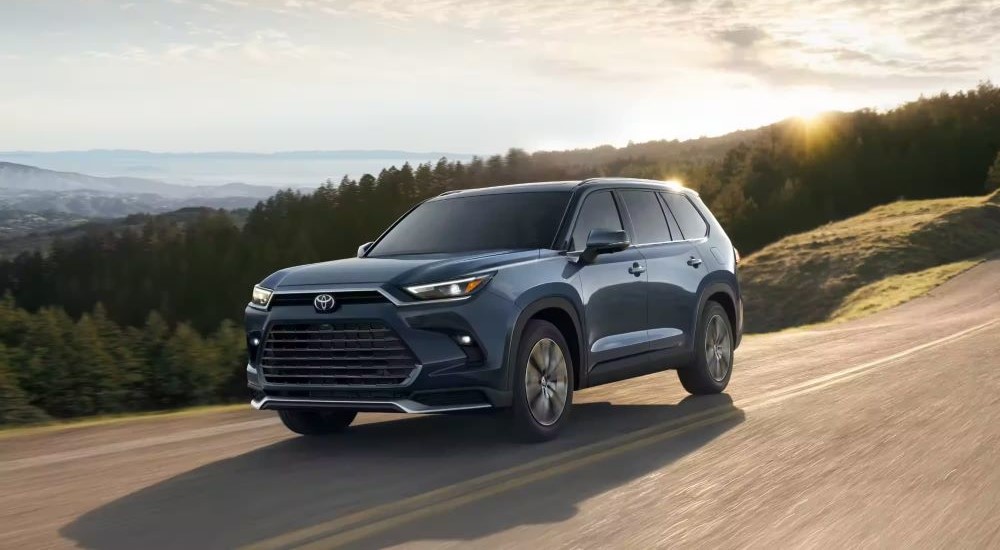 A blue 2024 Toyota Grand Highlander is shown driving from a Toyota dealer.