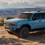 A blue 2024 Toyota Land Cruiser is shown parked off-road after visiting a Toyota dealer.