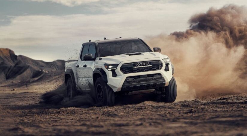 A white 2024 Toyota Tacoma is shown driving off-road.
