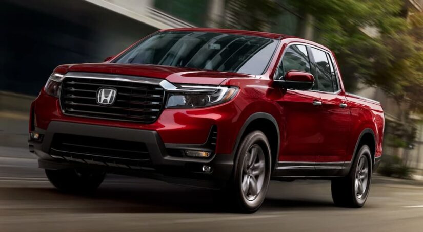 A red 2024 Honda Ridgeline RTL-E is shown driving from a dealer with a Honda Ridgeline for sale.