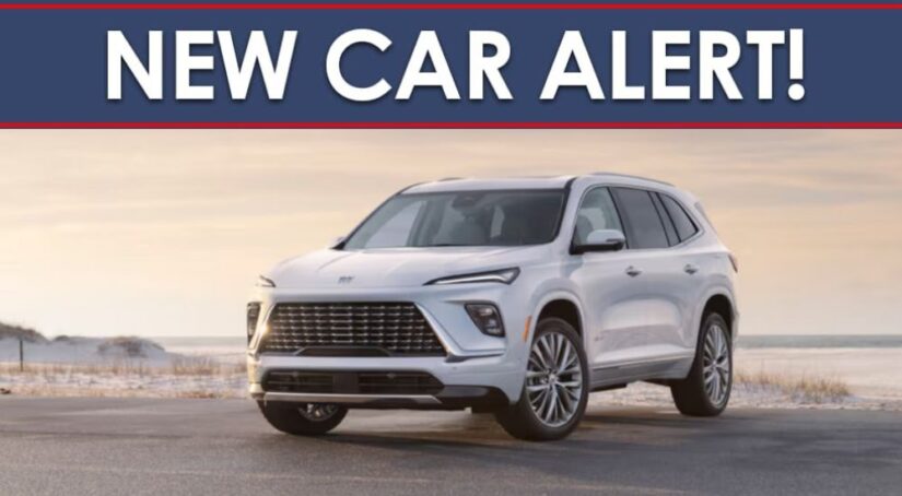 A New Car Alert banner is shown above a white 2025 Buick Enclave parked near a beach.