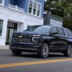A black 2025 Chevy Suburban High Country driving on a residential street.