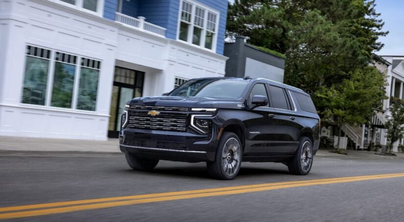 A black 2025 Chevy Suburban High Country driving on a residential street.