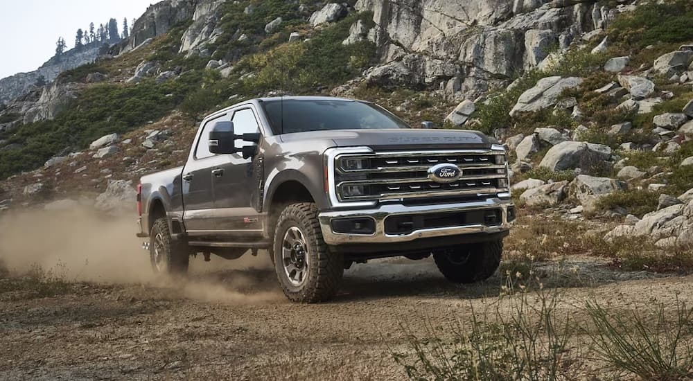 A black 2024 Ford F-250 Tremor driving on a dusty trail after visiting a Ford dealer.