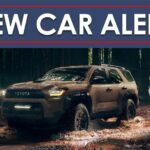 A brown 2025 Toyota 4Runner driving through muddy water in the woods under a New Car Alert banner.