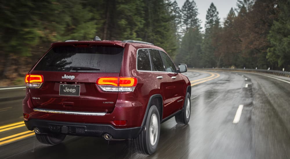 Rear view of a red 2020 Jeep Grand Cherokee driving in the rain.