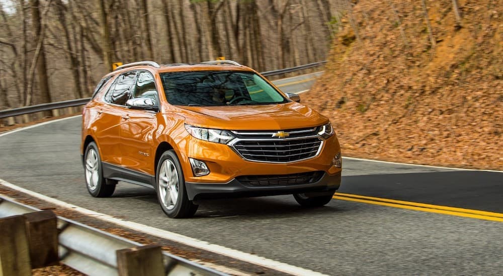 An orange 2019 Chevy Equinox driving on a curving road.