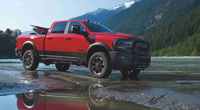 A red 2024 Ram 2500 for sale is shown from the side while parked in a creek.