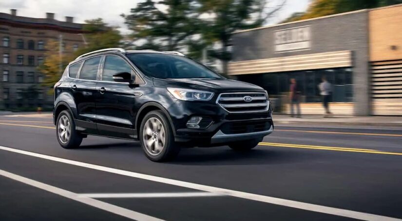 A black 2019 Ford Escape is shown driving in a city after visiting a dealer with a used Ford Escape for sale.