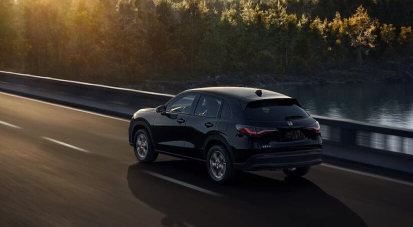 A black 2024 Honda HR-V LX is shown driving on a bridge after viewing a Honda HR-V for sale.