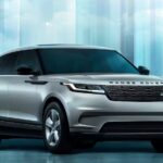 A silver 2024 Range Rover Velar is shown parked in a blue room.