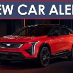 A new car alert banner is shown above a red 2025 Cadillac OPTIQ.