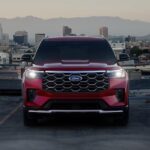 A red 2025 Ford Explorer Platinum is shown parked near a city.