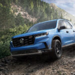 A blue 2025 Honda Pilot TrailSport off-roading down a rocky mountain.