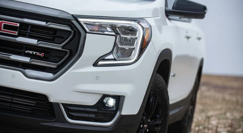 A close up of the front headlight and grille on a white 2022 GMC Terrain AT4.