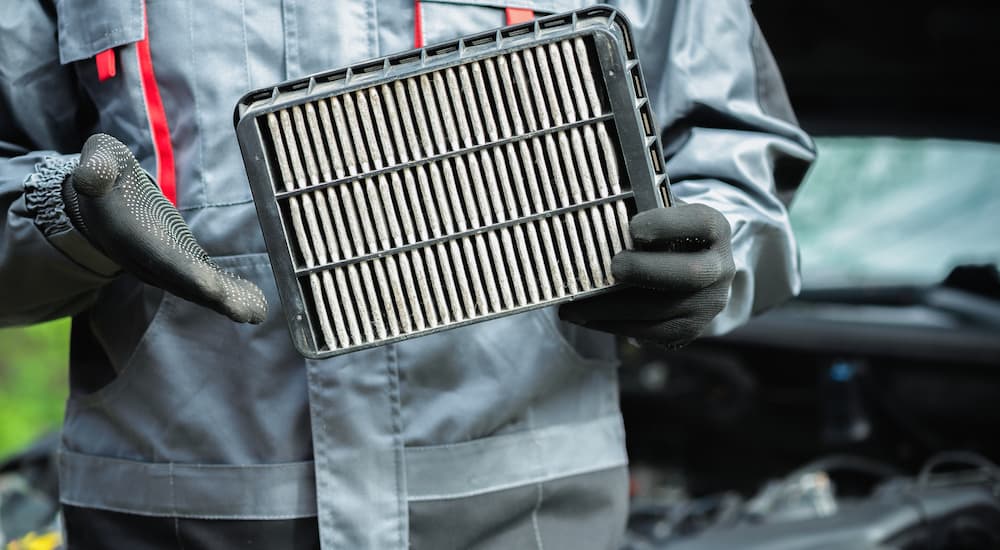 A mechanic holding an air filter for a vehicle.
