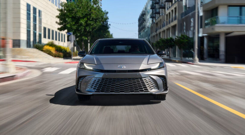 Head on view of a silver 2025 Toyota Camry XSE driving on a city street.