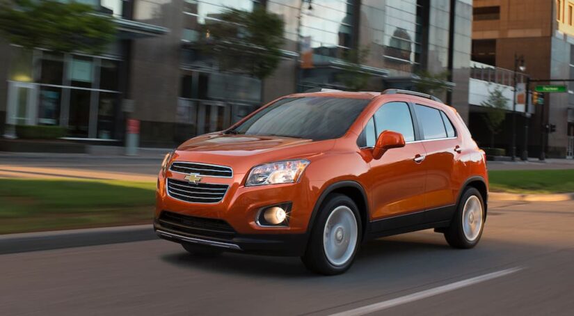 An orange 2016 Chevy Trax driving on a city street.