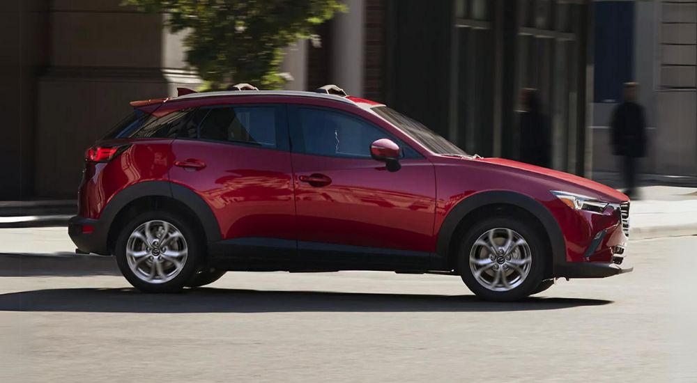 A red 2021 Mazda CX-3 is shown driving on a city street.