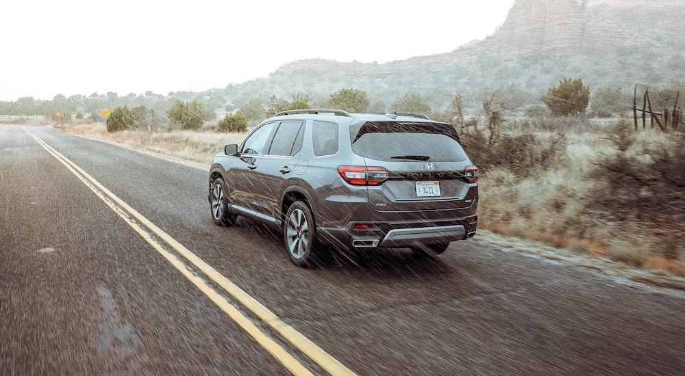 A silver 2025 Honda Pilot is shown from the rear at an angle.