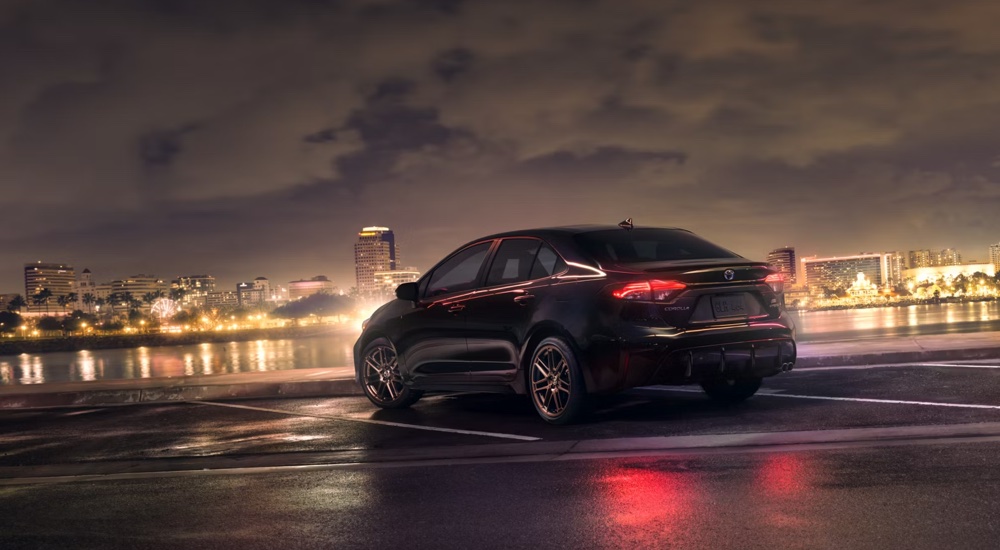 2024 Toyota Corolla Hybrid Nightshade parked near city lights at night.