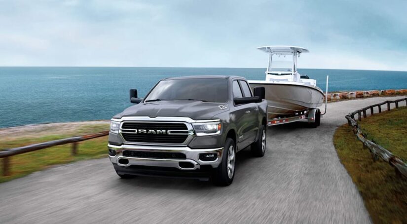 A used truck for sale, a grey 2020 Ram 1500 towing a boat.