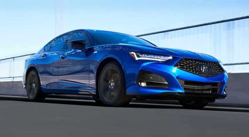 A blue 2023 Acura TLX A-Spec is shown driving on a bridge.