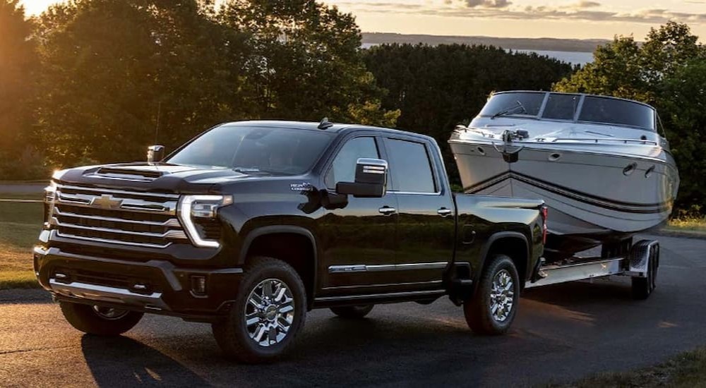 A black 2024 Chevy Silverado 1500 High Country is shown towing a boat.