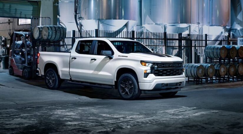 A white 2024 Chevy Silverado 1500 Rally Edition is shown parked near barrels.